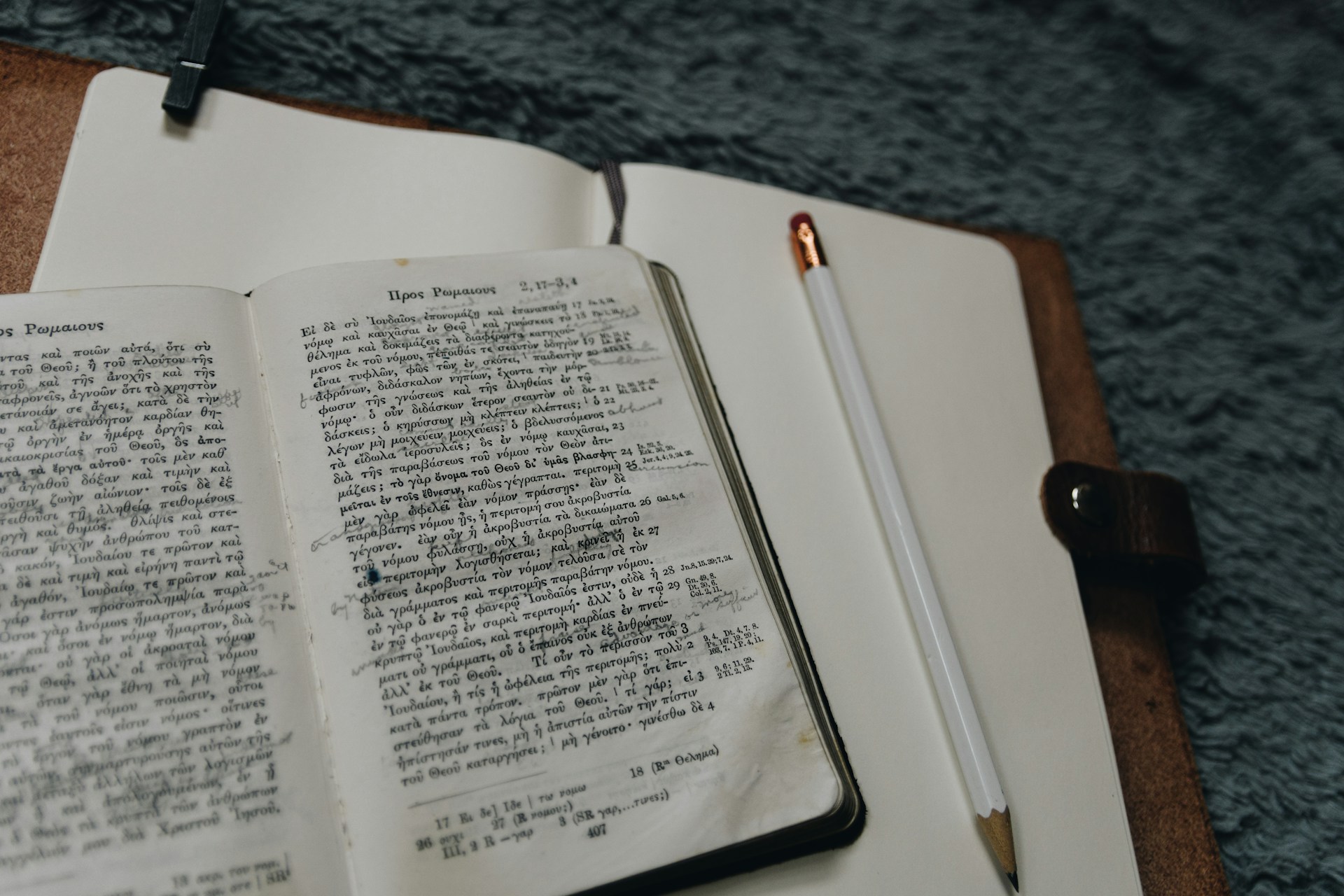 An annotated book in Greek on a writing pad, alongside a pencil.